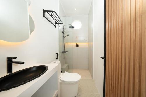 a bathroom with a black sink and a toilet at Bombora Surf Camp in Uluwatu
