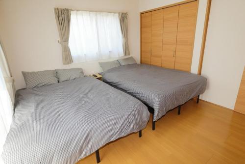 two twin beds in a room with a window at Dino Base in Mifune