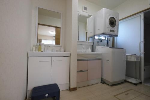 a white kitchen with a sink and a microwave at Dino Base in Mifune