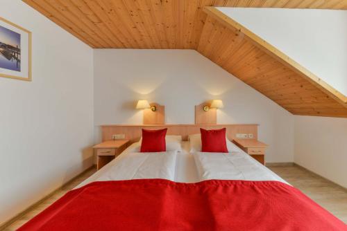 ein Schlafzimmer mit einem großen Bett mit roten Kissen in der Unterkunft Landhotel zum Metzgerwirt in Bayersoien