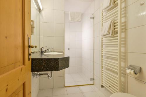 a white bathroom with a sink and a shower at Landhotel zum Metzgerwirt in Bayersoien