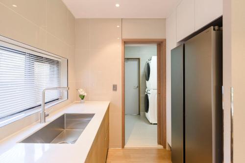 a kitchen with a sink and a refrigerator at The Brighton Hamdeok in Jeju