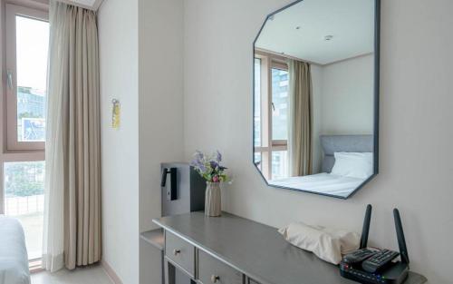 a mirror on a wall above a dresser in a room at BS Centum hotel in Busan