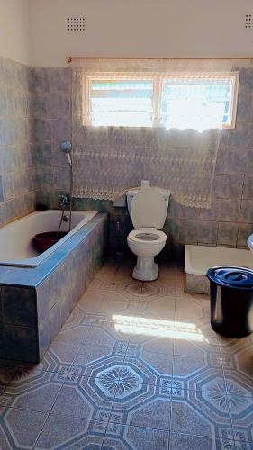a bathroom with a tub and a toilet and a bath tub at Quantico Guest house villa in Ndola