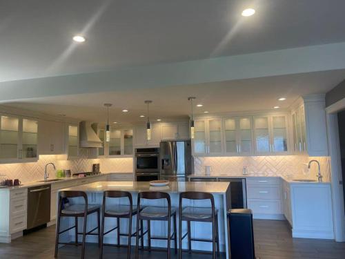 a kitchen with white cabinets and a island with bar stools at Sea view villa independent access in Nanaimo