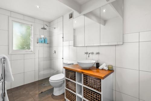 a white bathroom with a sink and a toilet at The Stables - Charming Loft with Derwent River Views in Sandy Bay
