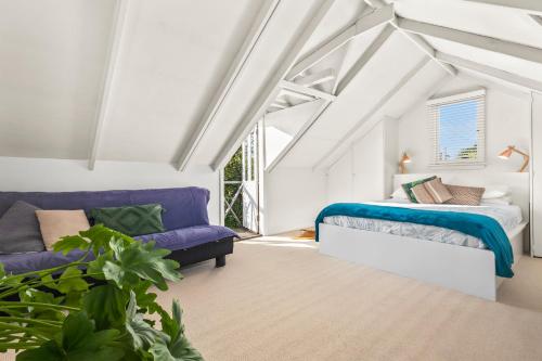 a attic bedroom with a bed and a couch at The Stables - Charming Loft with Derwent River Views in Sandy Bay