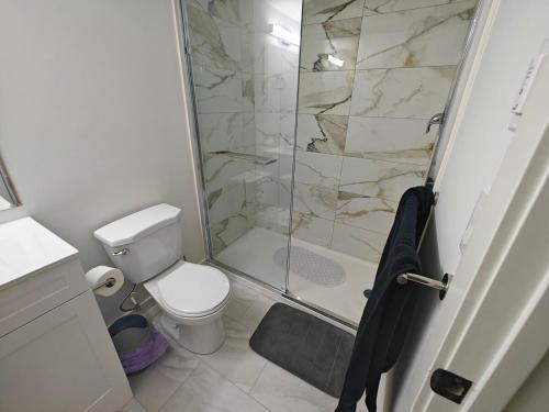 a bathroom with a toilet and a glass shower at New Haven- 2-Bedroom Suite in Winnipeg