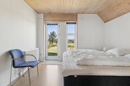a bedroom with a bed and a blue chair at Spacious Holiday Home With Water View in Redsted