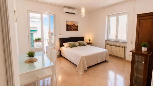 a bedroom with a bed and a table and windows at Casa Giusto Ischia 3 in Ischia Town