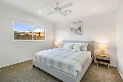 a white bedroom with a bed and a window at Kinma Valley Retreat KVR in Morayfield