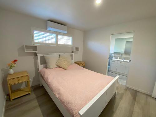 a small bedroom with a bed with a pink blanket at Charming Beach Getaway in Valla Beach