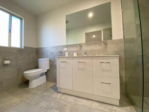 a bathroom with a toilet and a sink and a mirror at Charming Beach Getaway in Valla Beach