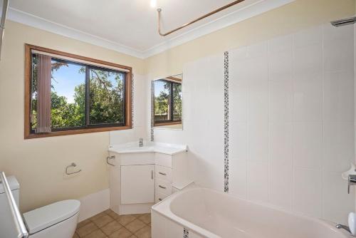 a bathroom with a tub and a toilet and a sink at Coastal Charm in Valla Beach