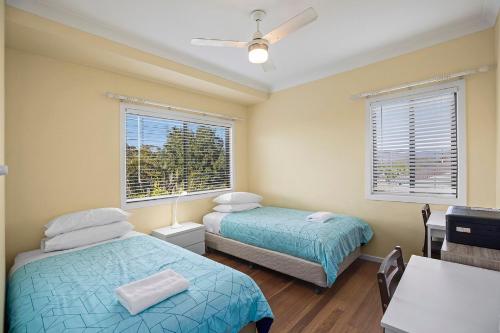 ein Zimmer mit zwei Betten, einem Tisch und zwei Fenstern in der Unterkunft 8Tuna in Valla Beach