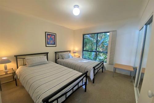 two beds in a room with a window at Estuary in Nambucca Heads