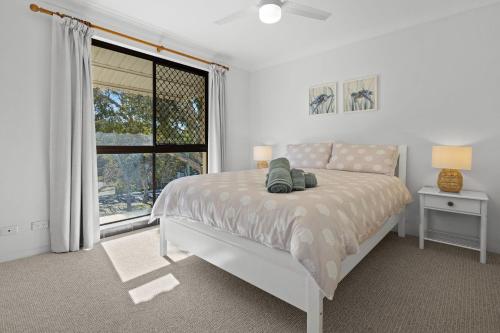 a white bedroom with a bed and a window at Coastal Chill in Nambucca Heads