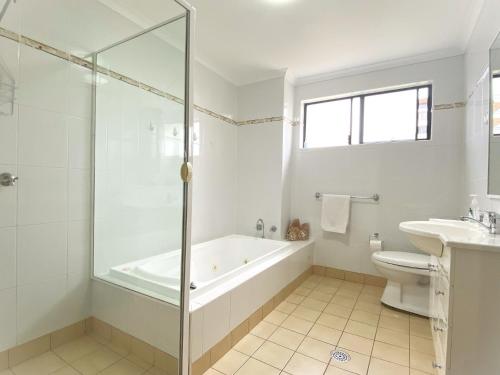 a bathroom with a tub and a toilet and a sink at Karingal in Nambucca Heads