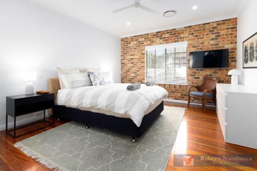 a bedroom with a bed and a brick wall at 57Charlton in Nambucca Heads
