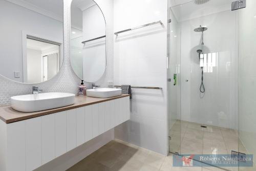 a white bathroom with two sinks and a mirror at 57Charlton in Nambucca Heads