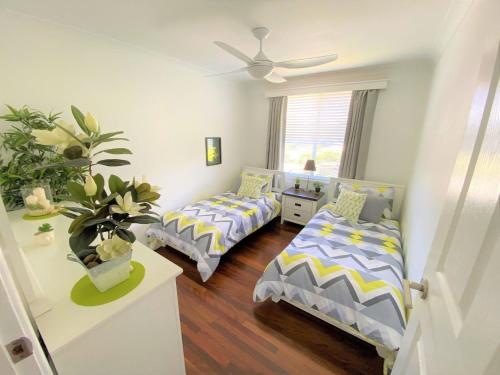 a bedroom with two beds and a ceiling fan at Riverwood in Nambucca Heads