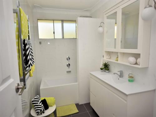 a white bathroom with a tub and a sink at Riverwood in Nambucca Heads