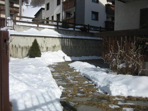 a snow covered walkway with snow in front of a building at Residence Casa Federica in Valfurva