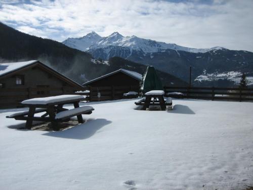 two picnic tables in the snow with mountains in the background at Residence Casa Federica in Valfurva