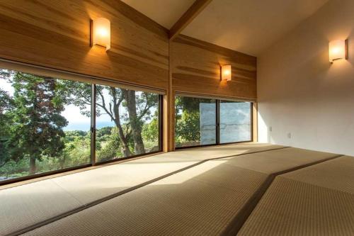 a bedroom with a large bed and large windows at Cottage Views in Yakushima