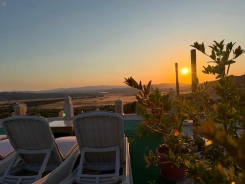 a couple of chairs sitting on a patio with the sunset at Under Stars in Nebeur