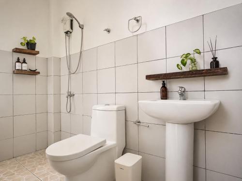 a white bathroom with a toilet and a sink at Pascoe's Units Siargao- Suites in General Luna