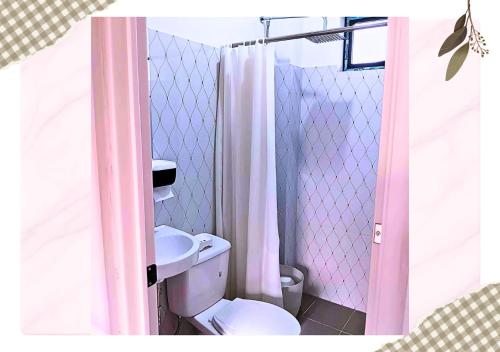 a bathroom with a pink shower curtain and a toilet at MartiVille Residences in Gloria
