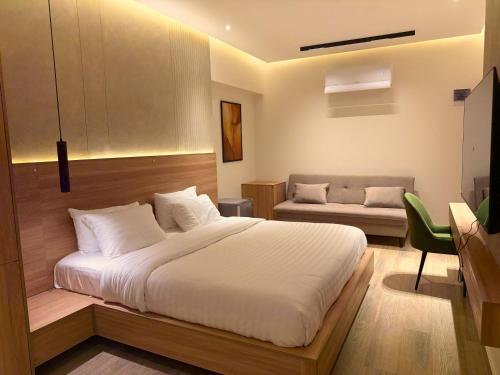 a bedroom with a large white bed and a couch at Hamsun DHA in Karachi