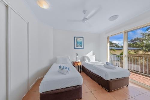 two beds in a room with a balcony at Beach Court - Airlie Beach in Airlie Beach