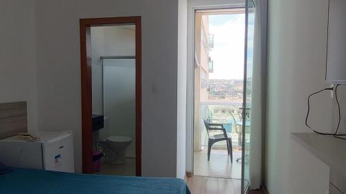 a bedroom with a bed and a glass door to a balcony at Lagoa Flats in Lagoa Santa