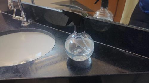 a glass bottle with a faucet on a bathroom sink at Lagoa Flats in Lagoa Santa