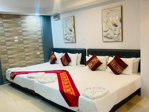a bedroom with two beds with red and white pillows at Pongsakorn Boutique Resort in Lat Krabang
