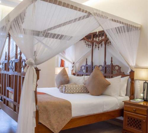 a bedroom with a canopy bed with white sheets and pillows at Nature villas Bentota in Bentota