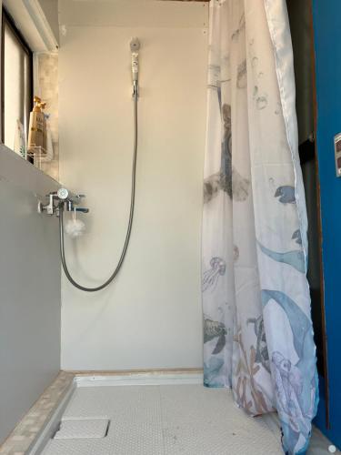 a shower in a bathroom with a shower curtain at 民泊ひなたぼっこ1日1組限定離れ貸切 in Nagano