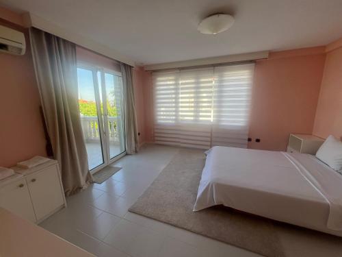 a bedroom with a white bed and a large window at Panorama Hills Villa with Pool in Thessaloniki