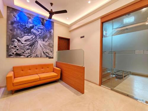 a lobby with an orange couch and a large painting at Hotel Sai Residency in Karjat