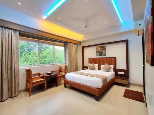 a hotel room with a bed and a desk and a window at Hotel Sai Residency in Karjat