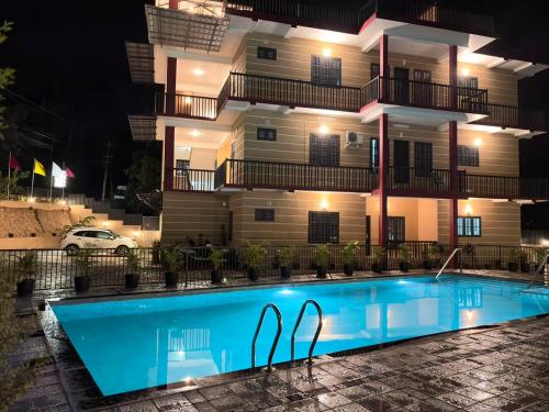 a swimming pool in front of a building at night at The Rosetta Inn, Wayanad in Wayanad