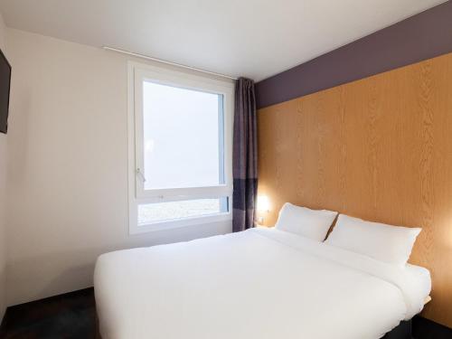 a bedroom with a large white bed and a window at B&B HOTEL Marne-La-Vallée Torcy in Torcy