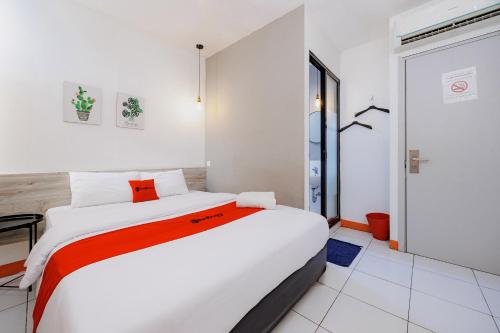 a bedroom with a large white bed with orange accents at RedDoorz near Mangga Dua Mall in Jakarta