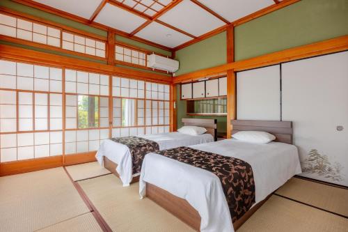 two beds in a room with windows at ジャポニークハウス in Sanmu