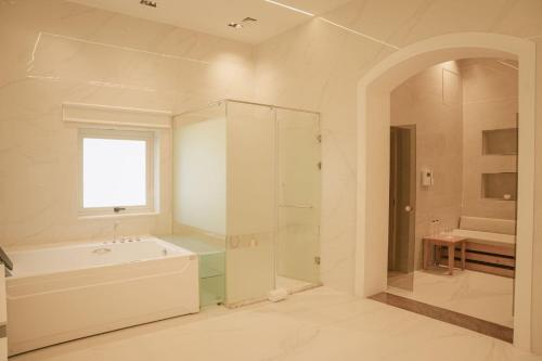 a bathroom with a shower and a tub and a sink at Jimma Palace Hotel in Jīma