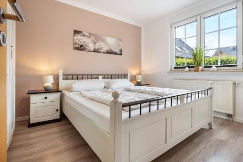 a bedroom with a large white bed and two windows at Haus 7 in Röbel