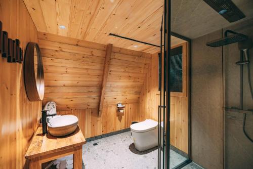 a wooden bathroom with a toilet and a shower at YEYU Hotel in Dujiangyan