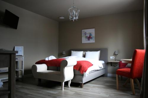 Un dormitorio con una cama con una manta roja y una silla. en B&B Rosteline, en Hamont